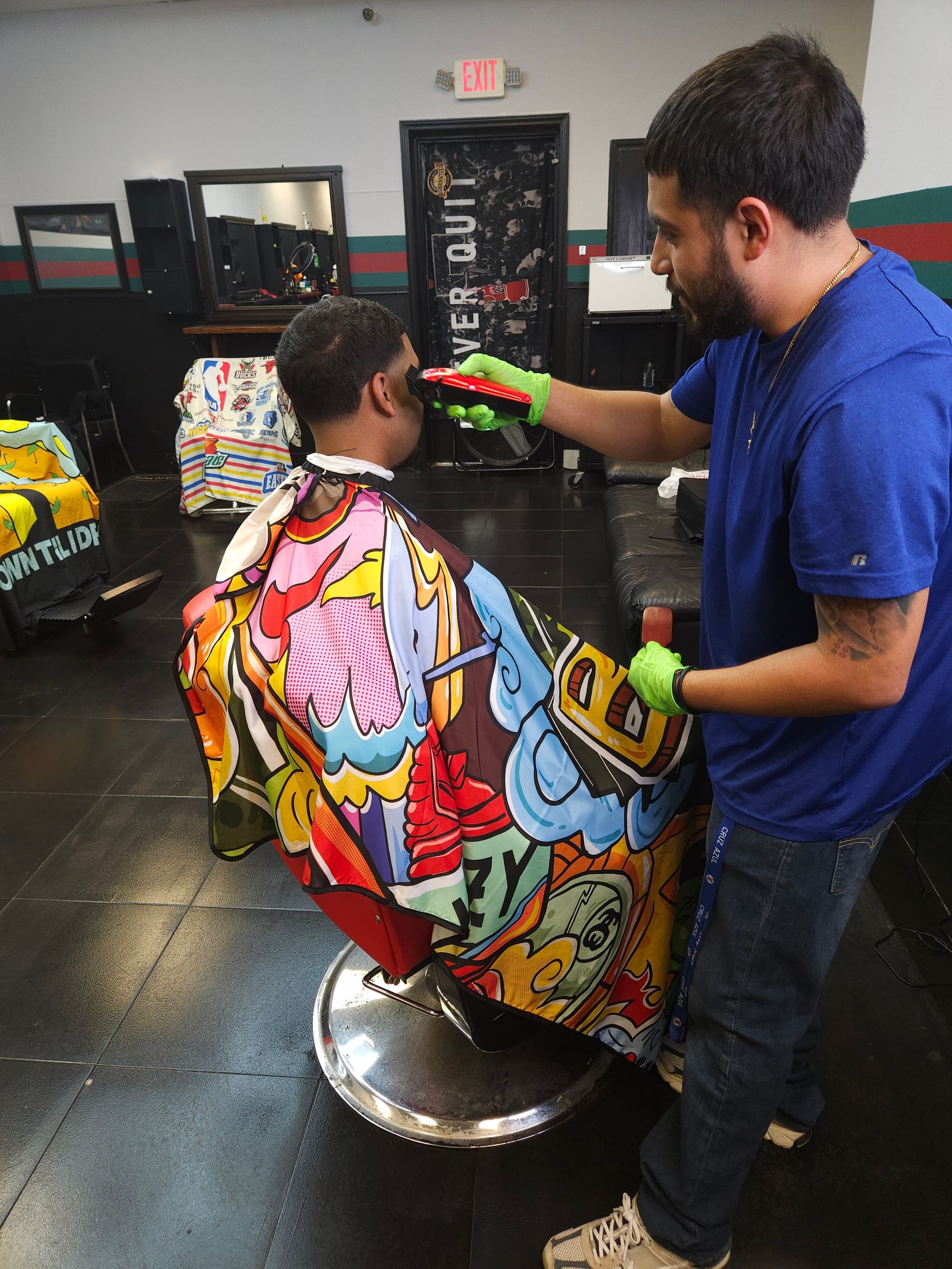 Barber trimming a client's hair in a colorful cape at a salon chair