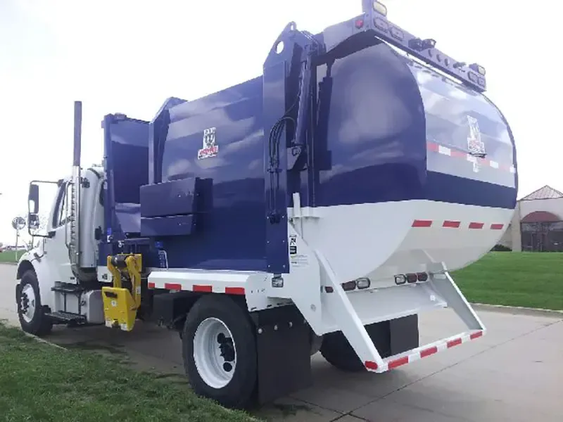 White and blue garbage truck parked on a street, side view