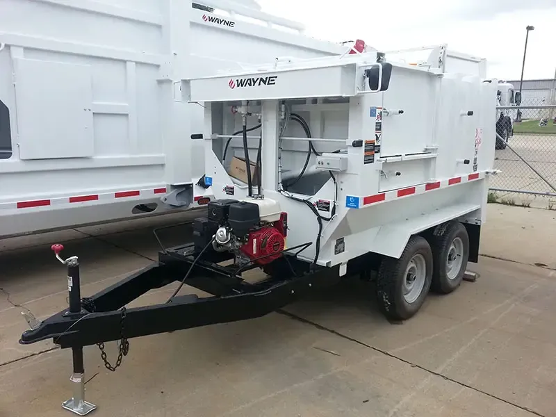 White utility trailer with a black tow hitch and rear wheels, parked beside a truck in an industrial lot