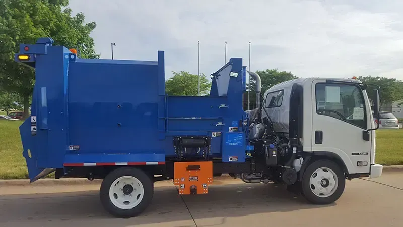 Blue garbage truck with white cab parked on a street