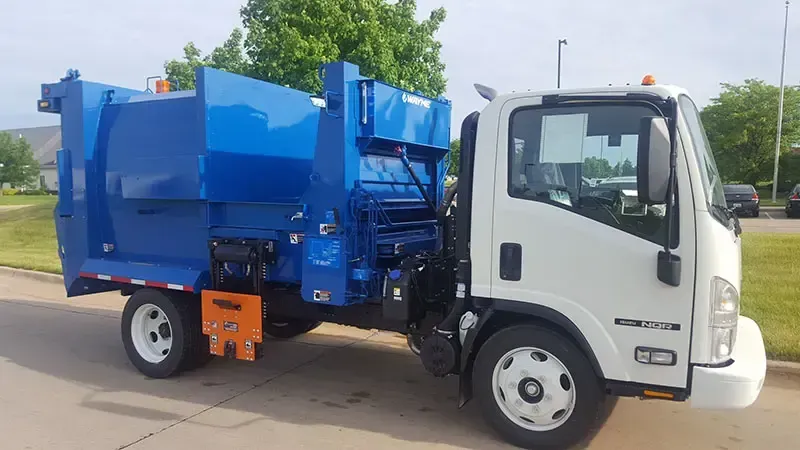 Blue and white garbage truck parked outdoors on a sunny street