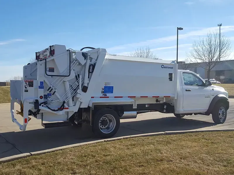 White utility truck with rear-mounted equipment parked roadside under a clear blue sky