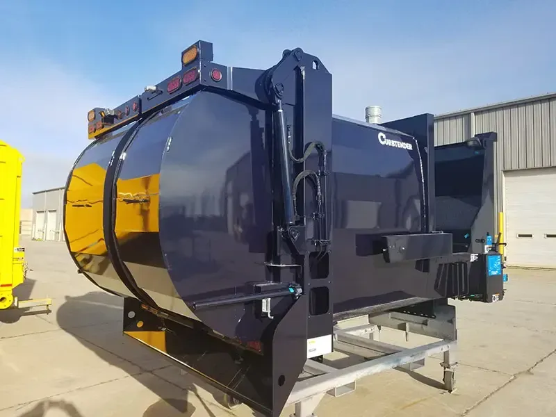 Large black industrial hopper with yellow side panel on a trailer in a warehouse yard.