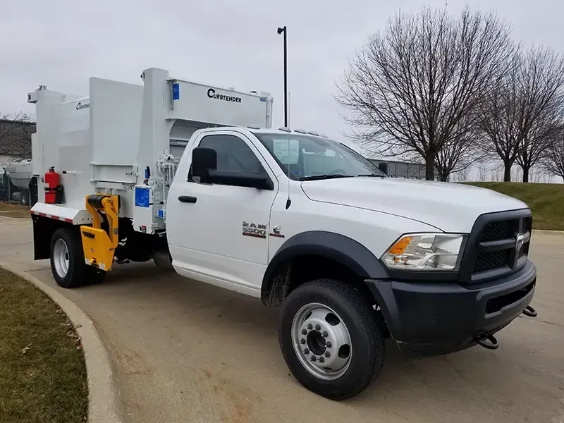 White utility truck with mounted equipment parked on a curved driveway near leafless trees