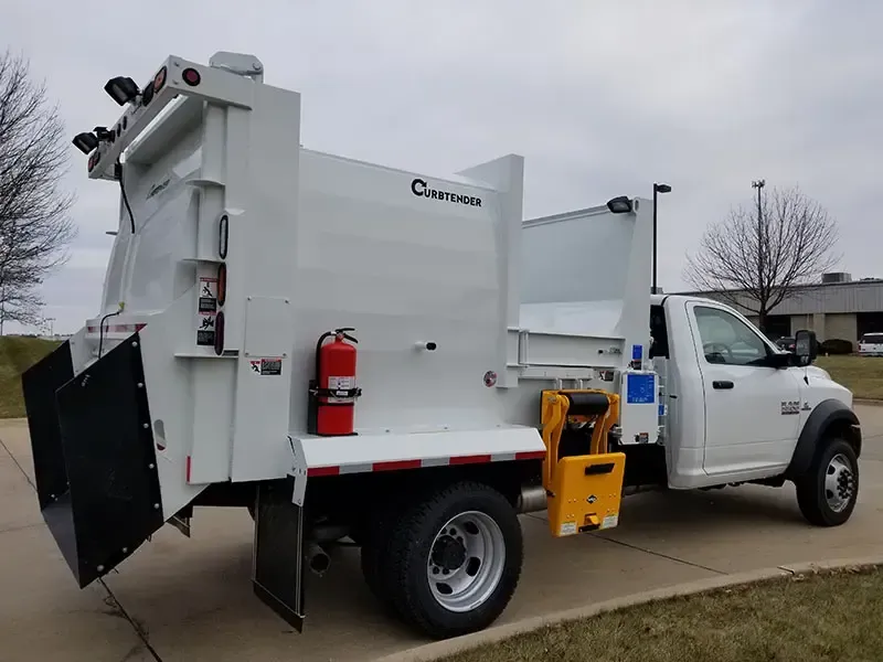 White utility bucket truck with raised work boom parked on a street, side compartments open