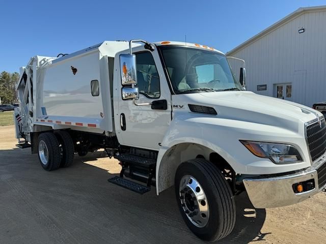 White garbage truck parked outside an industrial building on a sunny day