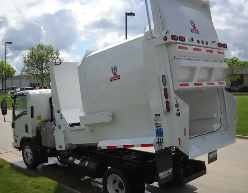 White garbage truck parked outdoors on a street, rear loading area open.