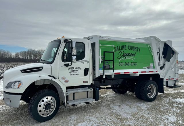 White garbage truck with green logo parked on a snowy lot under an overcast sky