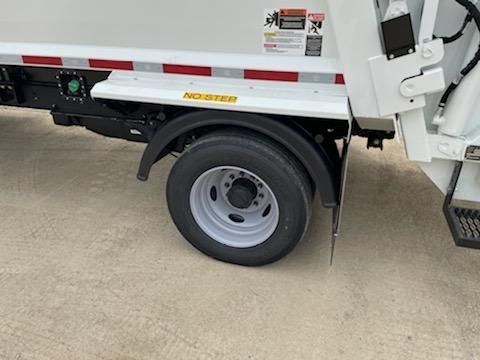 White utility truck with rear wheel and lift gate parked on concrete driveway