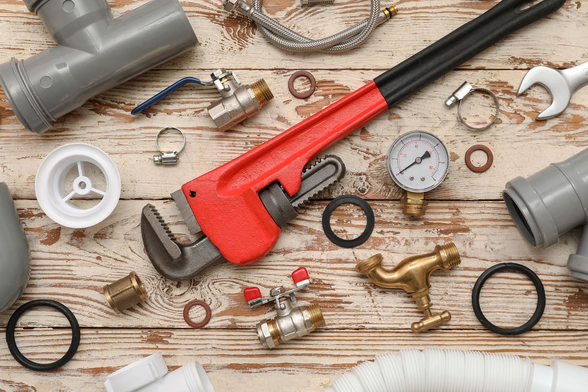 Plumbing supplies including pipe wrench, fittings, valves, and repair tools