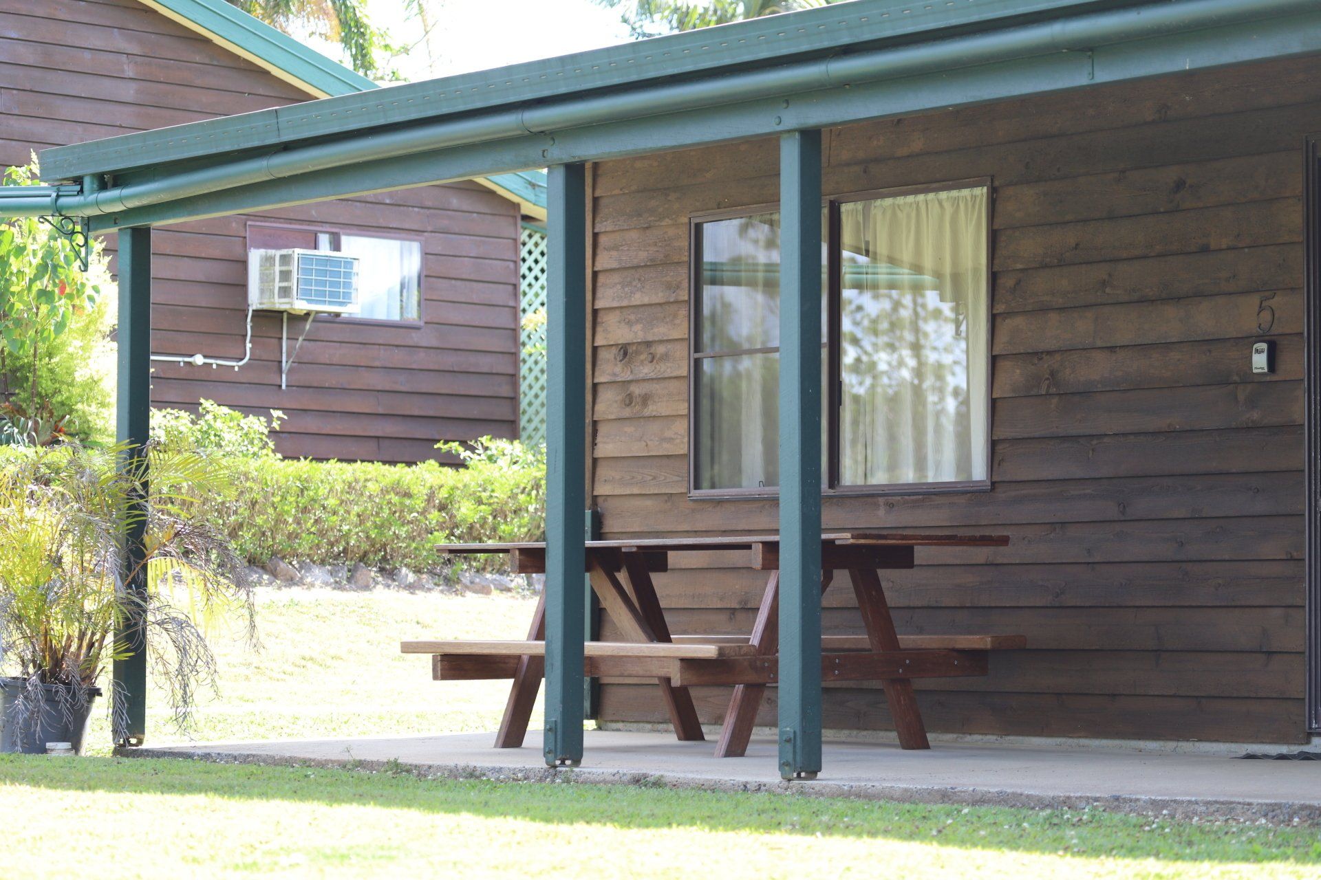 A wood cabin with a porch. A picnic table sits beneath the roof.