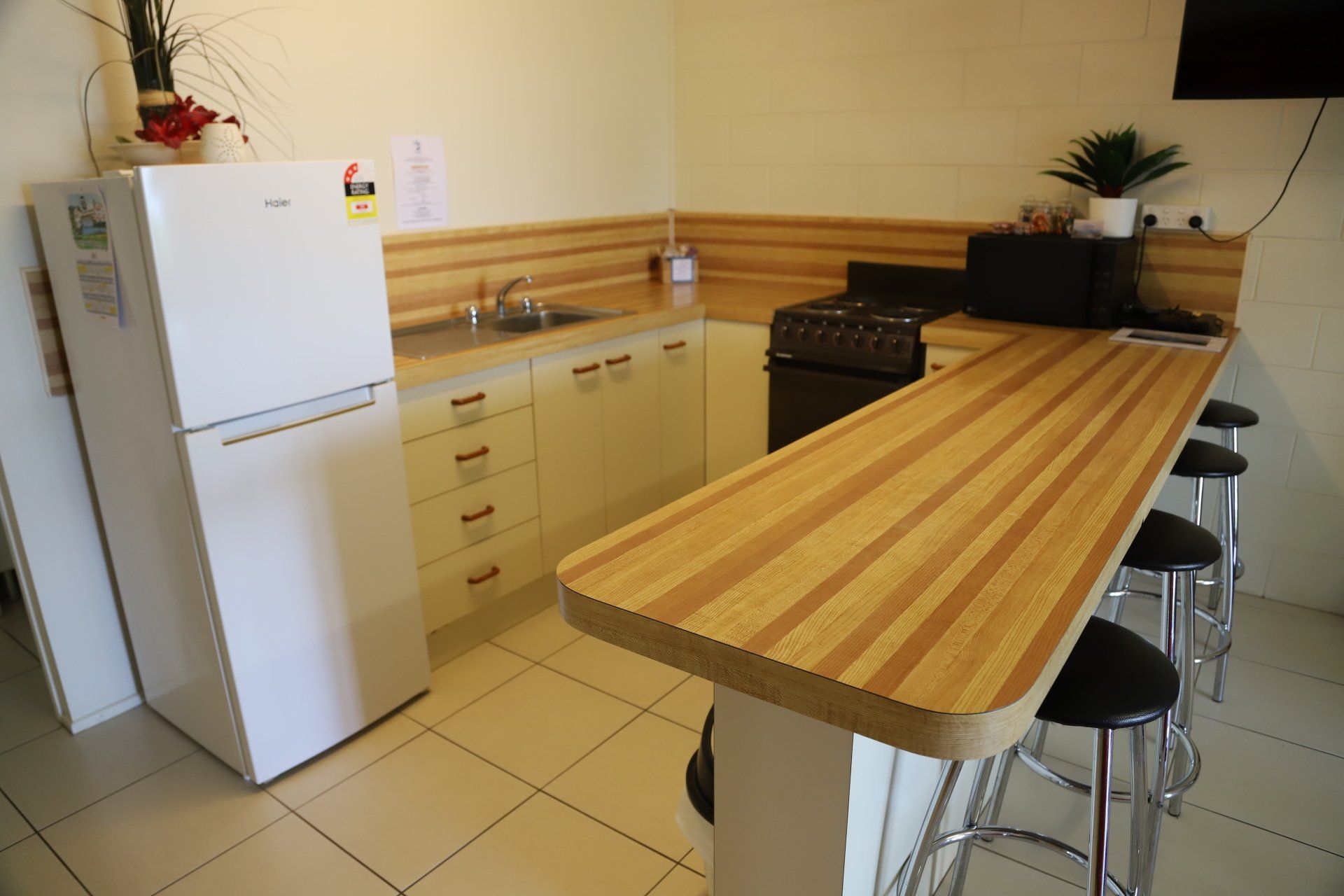 Kitchen with a refrigerator, cabinets, a stove, and a breakfast bar with stools.
