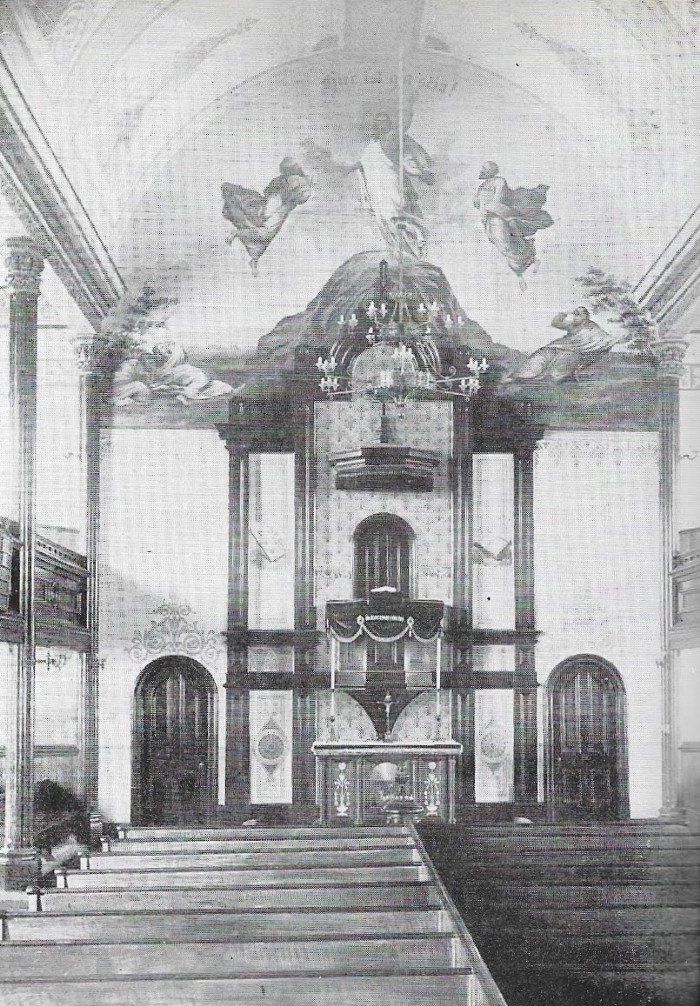 Interior view of an old church. Stone altar with arched doors. Ceiling painted with angel figures.