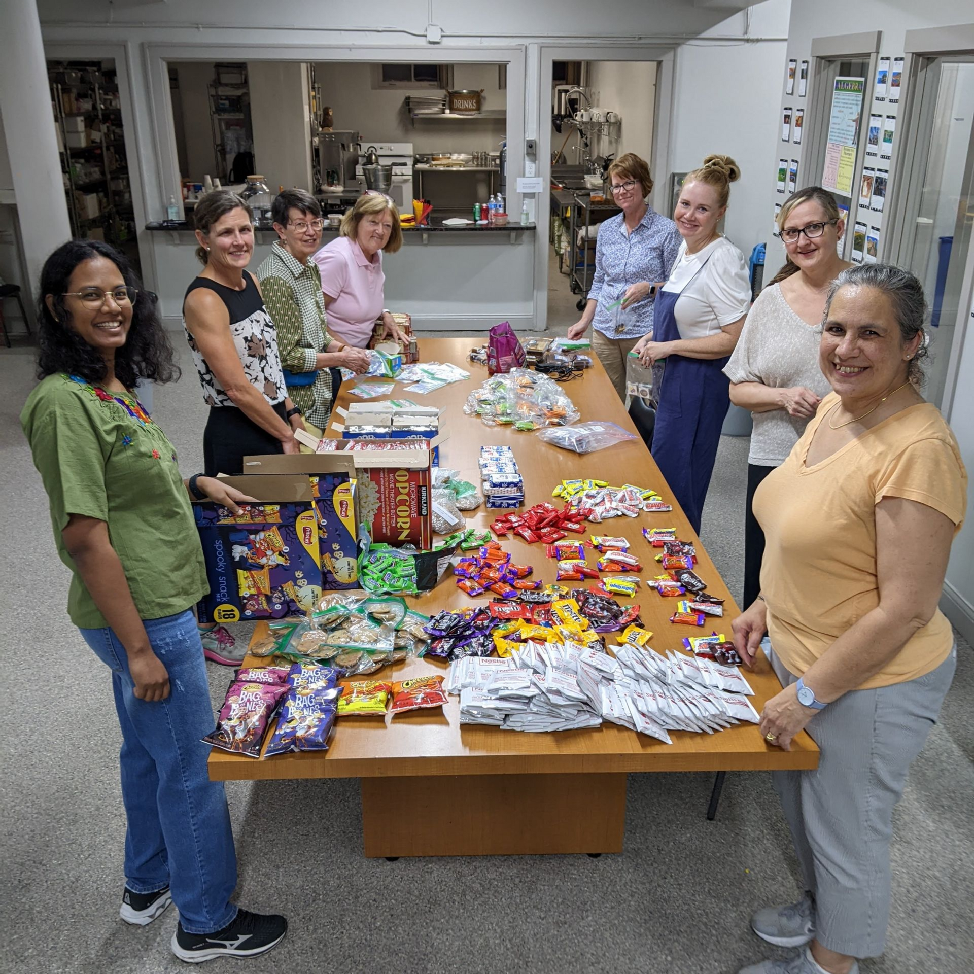 Eight people around a table sorting food items in a well-lit room.