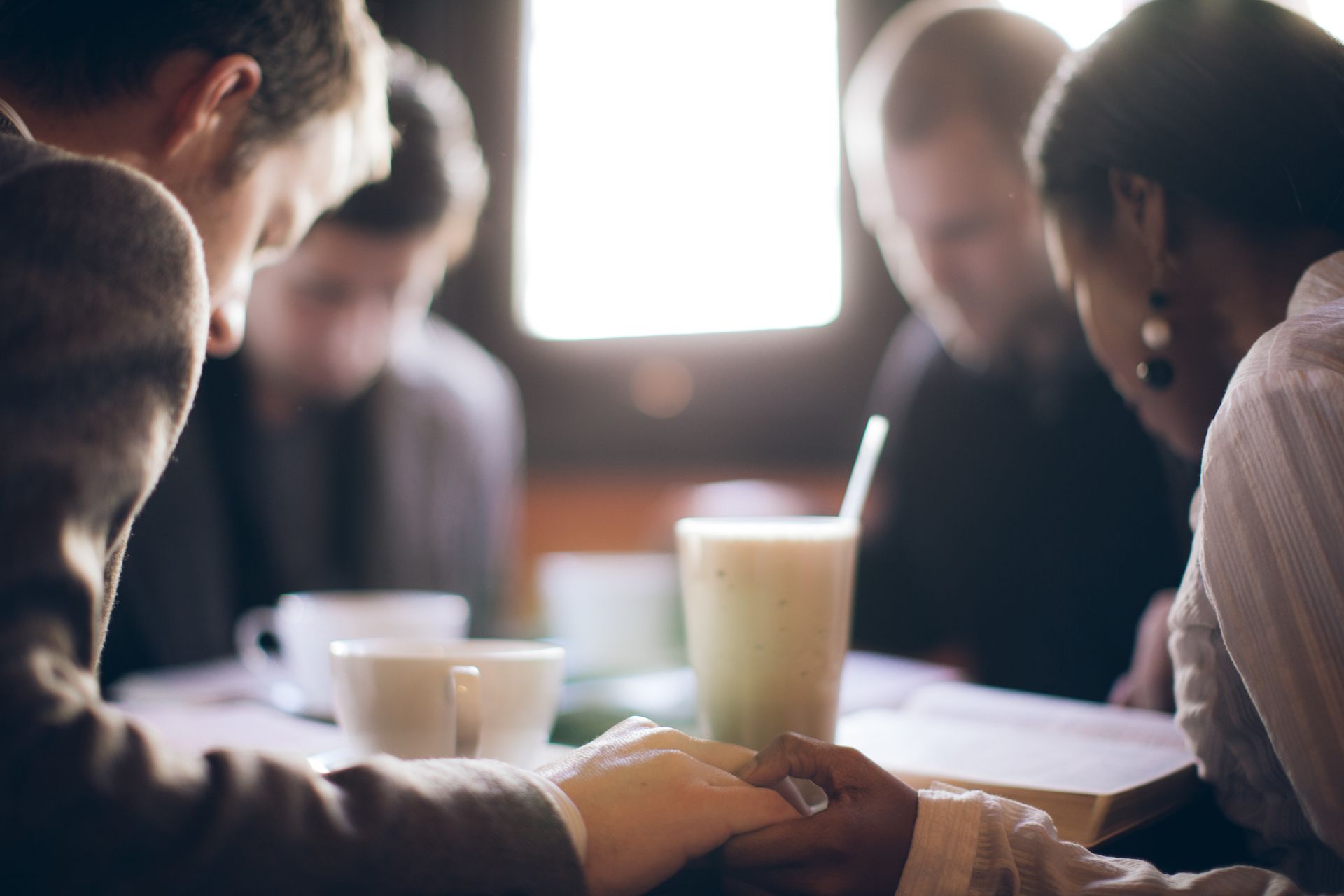 People gathered around a table in a bright meeting room, talking over coffee and papers.