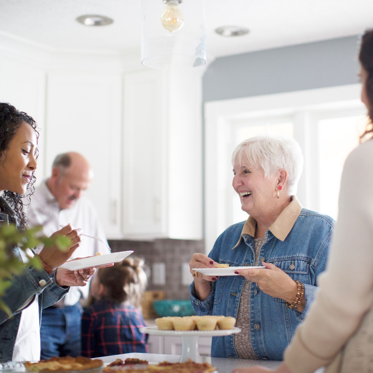 People sharing food and conversation in a bright kitchen during a casual gathering