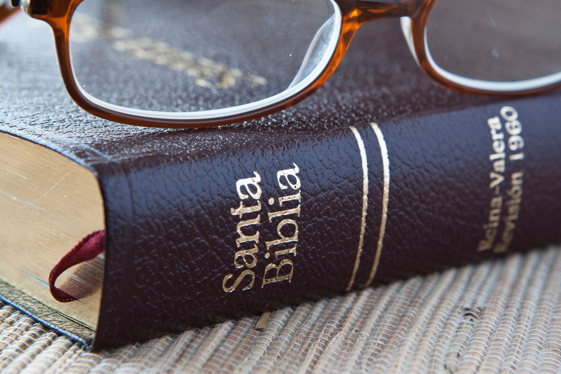 Glasses resting on a Santa Biblia book with a dark cover and ribbon bookmark