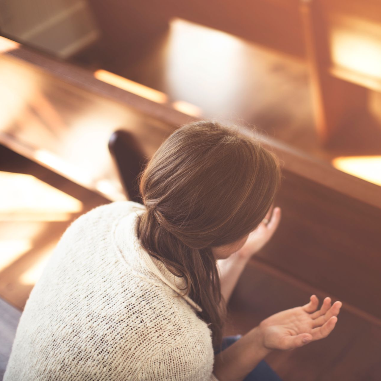 Person leaning over a wooden banister in a warmly lit indoor space