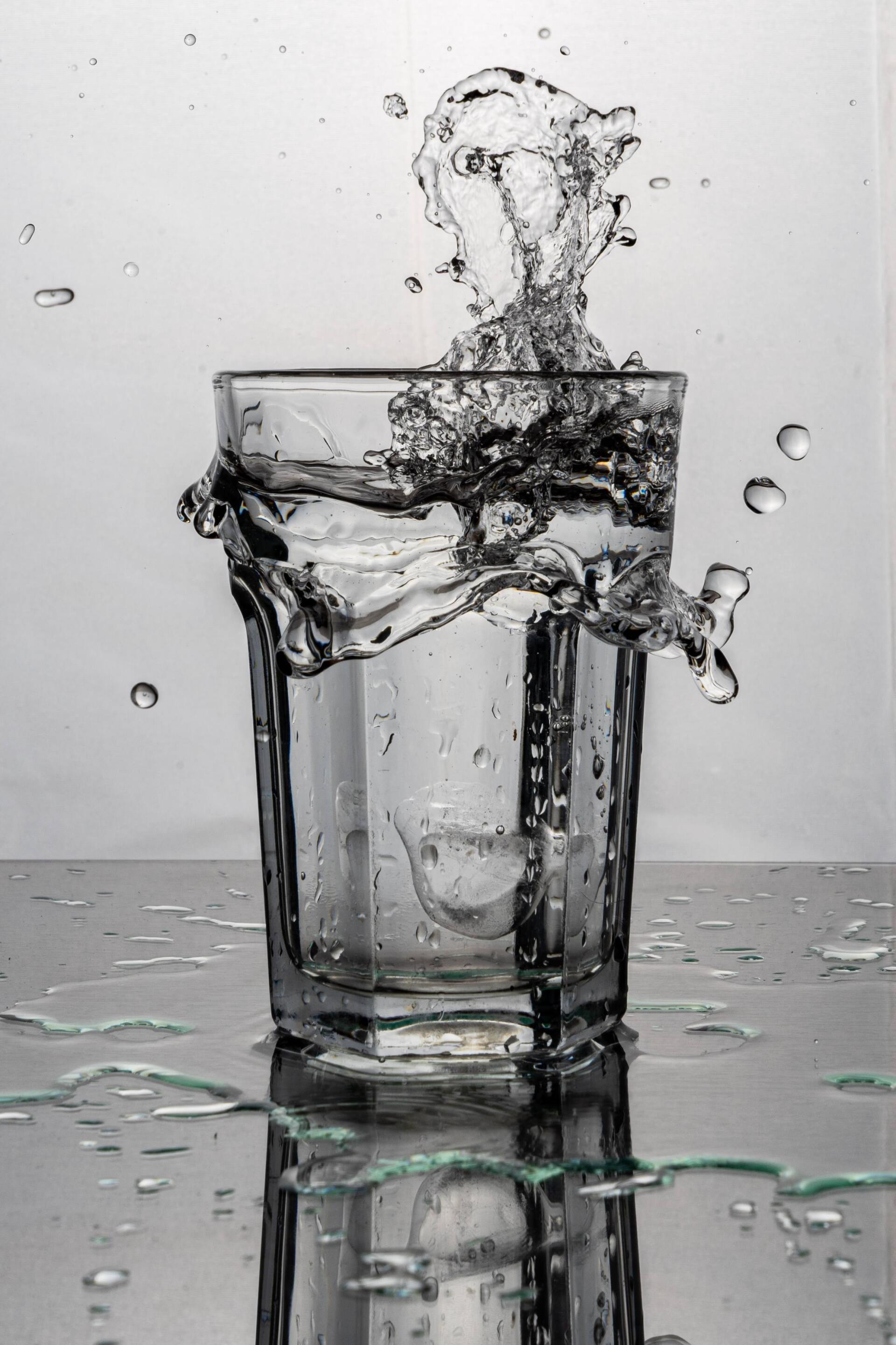 Un verre d'eau à moitié plein, l'eau éclabousse autour de lui.