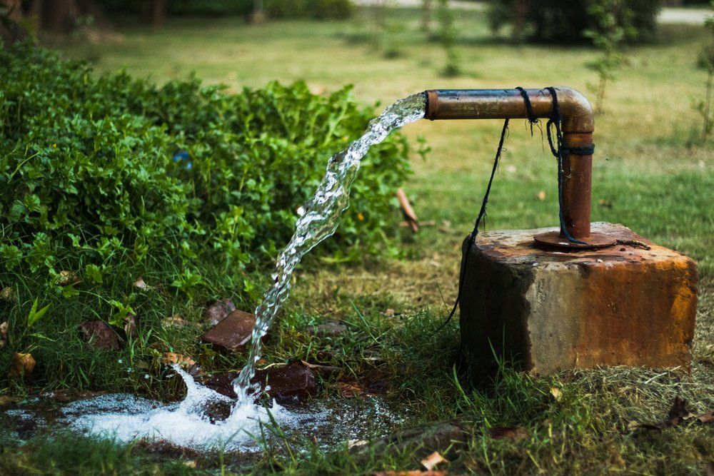 De l'eau sort d'un tuyau rouillé dans l'herbe.