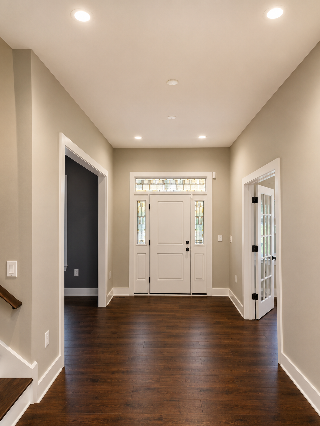 Empty hallway with dark hardwood floors, white double front doors, and recessed ceiling lights