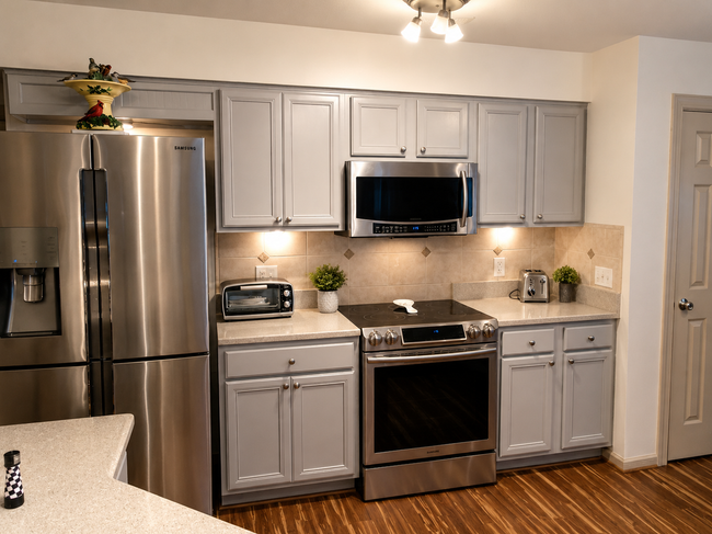 Modern kitchen with stainless steel appliances, gray cabinets, and light wood flooring