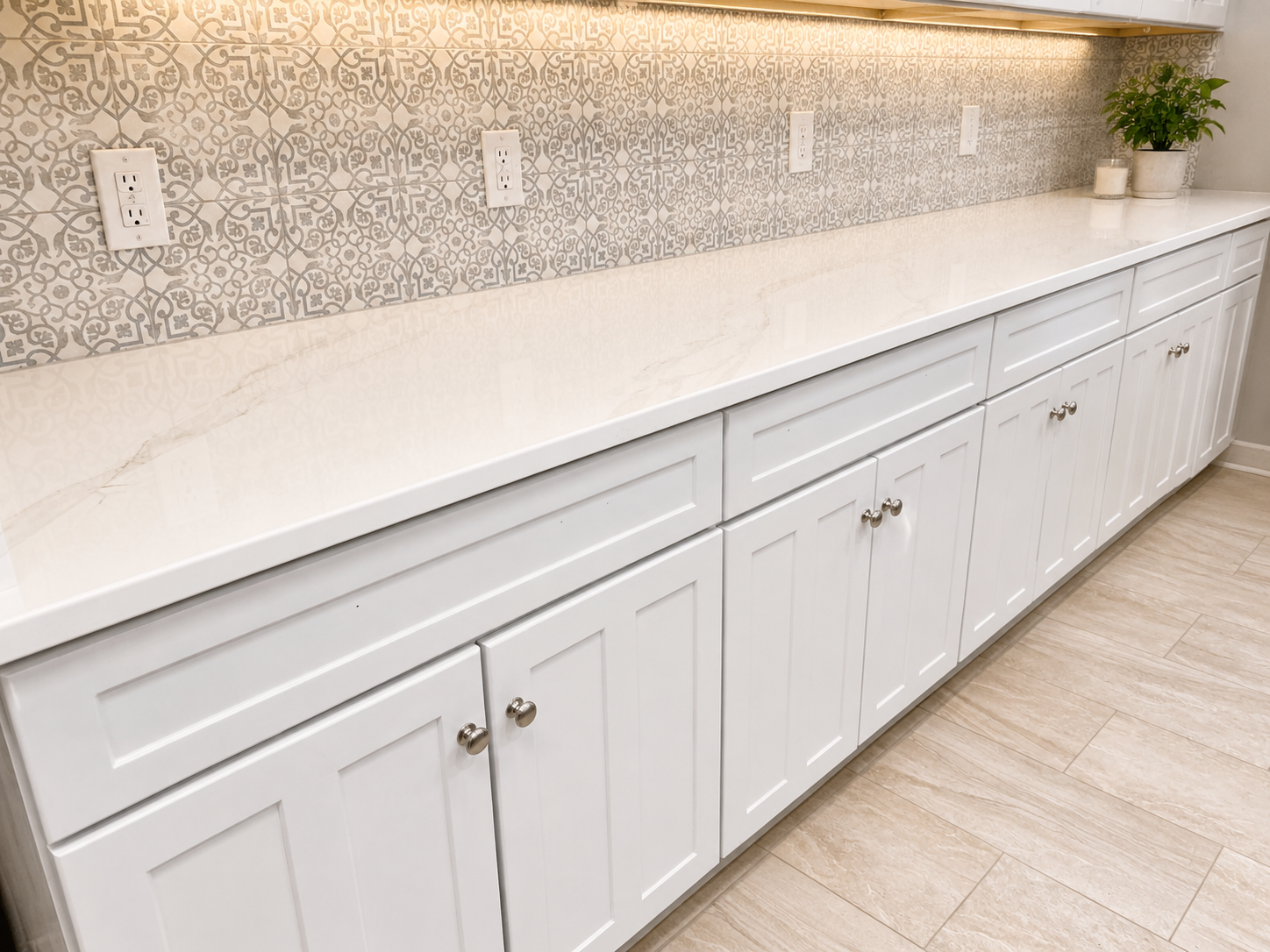 White kitchen countertop and cabinets with patterned backsplash and under-cabinet lighting