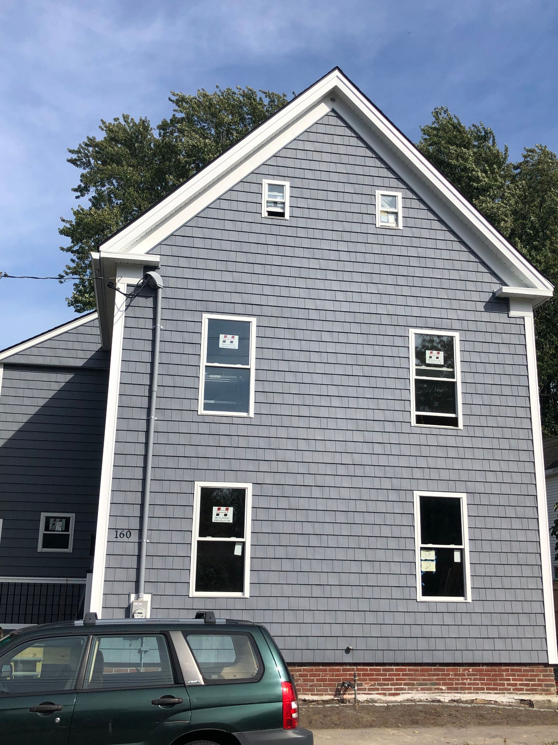 Blue clapboard house with newly installed white-framed windows, against a sunny sky.