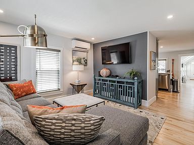 Cozy living room with gray sectional, TV on a gray wall, and teal console.