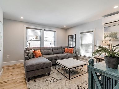Gray sectional sofa in a living room with windows, coffee table, and rug.