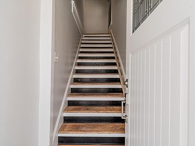 Staircase leading upwards with white walls and a partially open white door to the right.