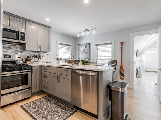Modern kitchen with gray cabinets, stainless steel appliances, and island. Hardwood floors.