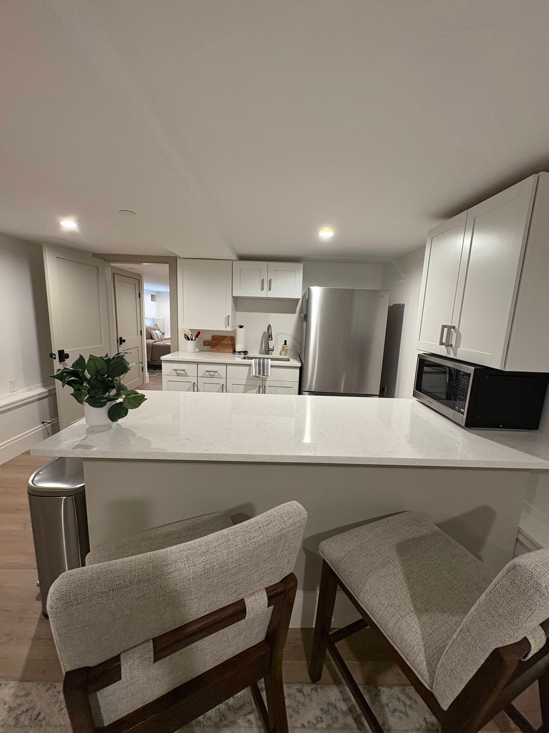 Kitchen with white cabinets, island with stools, and stainless steel appliances.