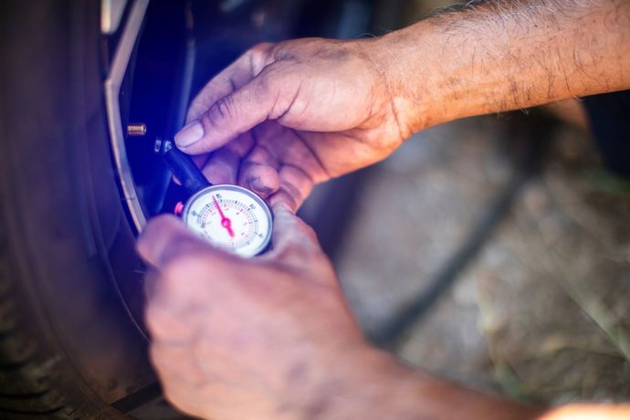 Di notte, delle mani usano un manometro per pneumatici per controllare la pressione di una ruota di bicicletta.