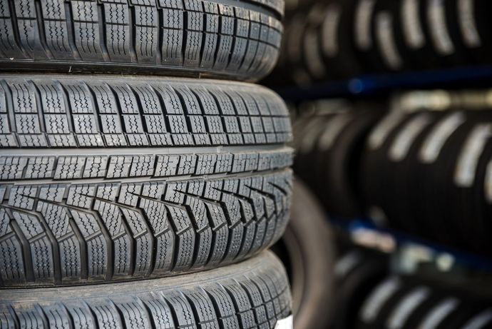 Pile di pneumatici neri in un magazzino, con pneumatici sfocati sullo sfondo.