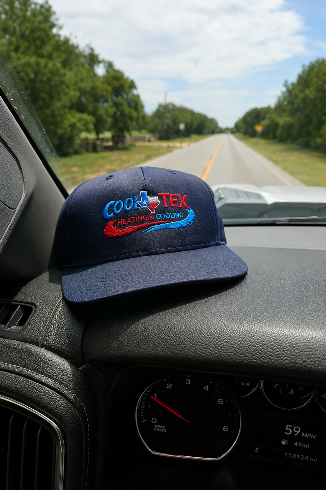 Blue-and-black cap on a car dashboard, with a quiet road and trees ahead through the windshield.
