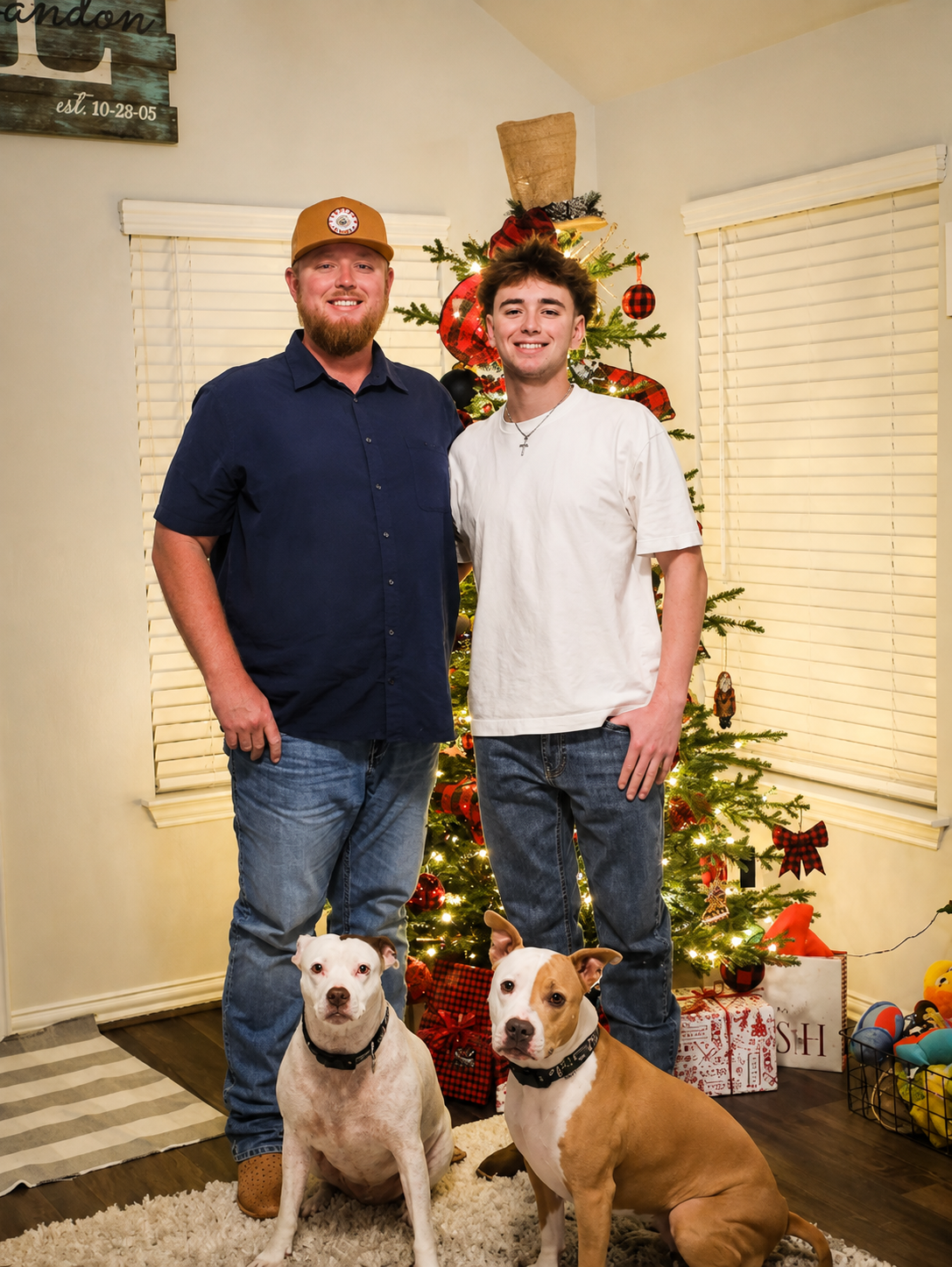 Two people with two dogs posing in front of a lit Christmas tree