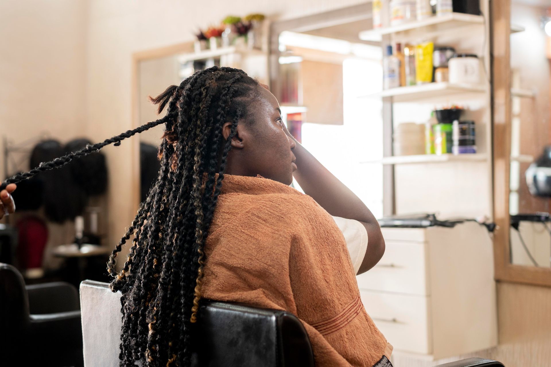 Hair stylist cutting client's hair in a salon. Both are wearing black.