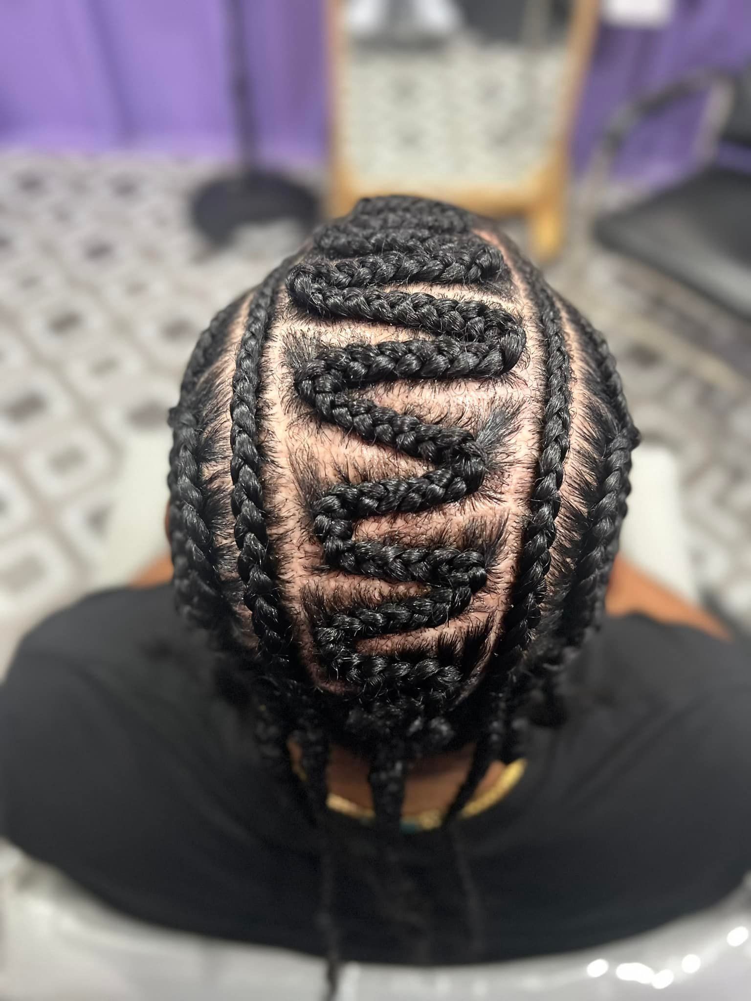 Top-down view of a person's head with neatly braided cornrows. Braids form a geometric pattern on the scalp.