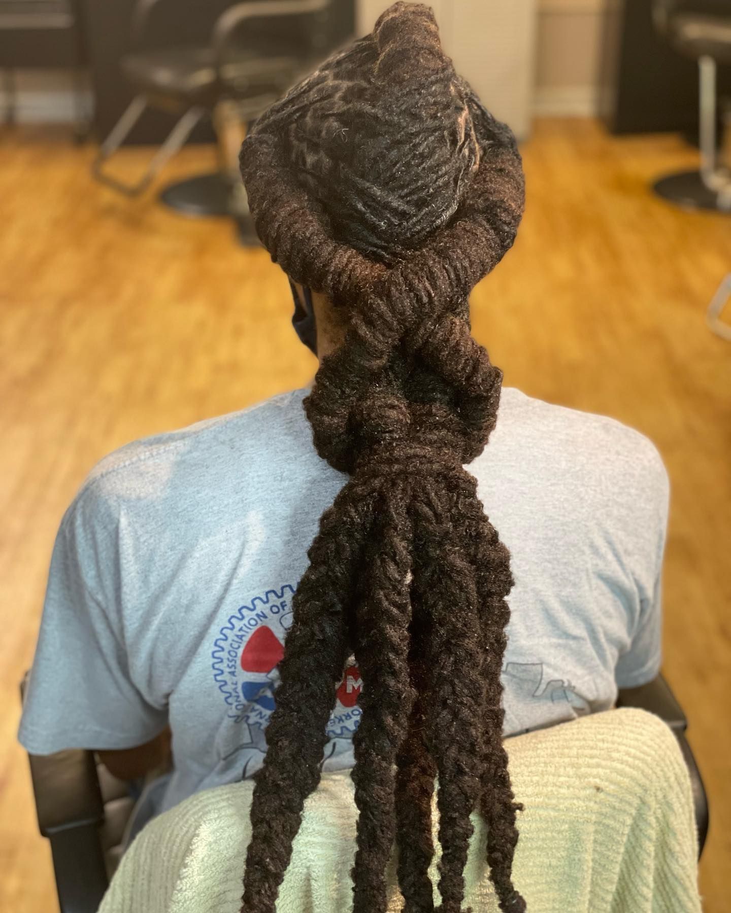 Person with dark locs styled into a knotted design on the head and a thick braid.