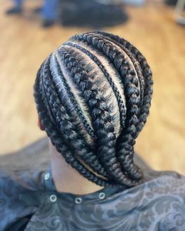 Braided hairstyle, dark hair, close-up, perspective from the back, multiple thick braids, in a salon setting.