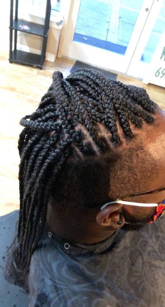 Person with braided hair and an undercut, sitting in a salon chair.