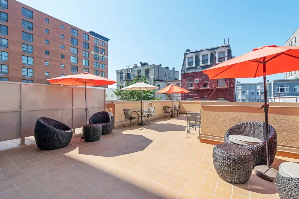 A patio with chairs and umbrellas in front of a building.
