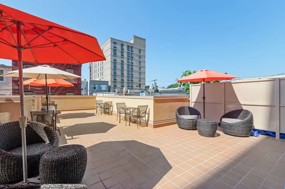 A patio with chairs , tables and umbrellas on a sunny day.