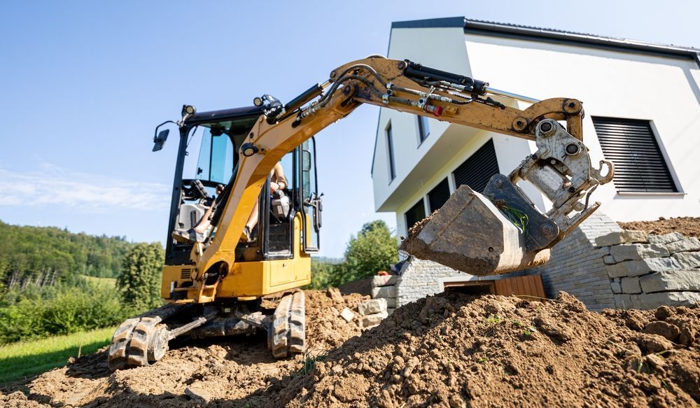 An excavator is digging a hole in front of a house.