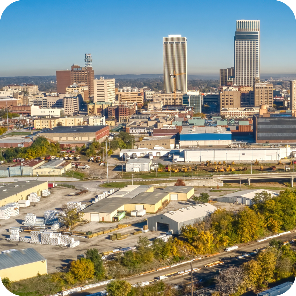 City skyline with tall buildings above a dense urban neighborhood under a clear blue sky