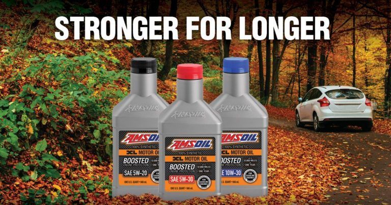 3 AMSOIL oil bottles with different colored caps, in front of fall foliage and a car on a road, 