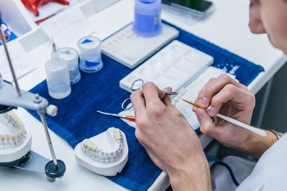 A Dentist is Working on a Model of Teeth — Central Coast Denture Clinic Erina In Terrigal, NSW