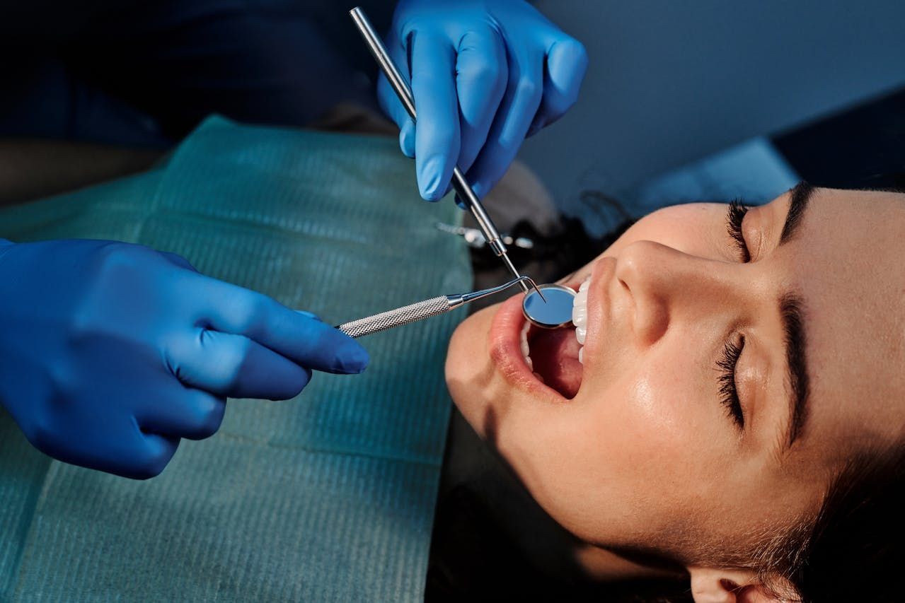 Dentist examining patient's teeth with tools in a dental office. — Central Coast Denture Clinic Erina In Erina, NSW
