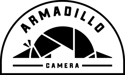 Armadillo Camera logo: black text and geometric shape inside an arch.